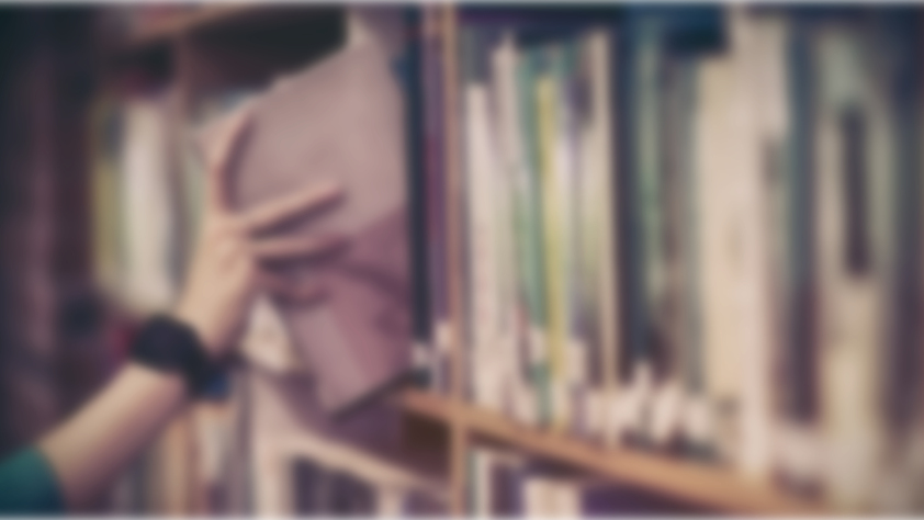 Blurred hand putting a book in between other books on a library shelf